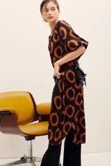 Vestido midi de viscosa color negro con estampado geométrico de círculos en tonos marrones y naranjas, de manga corta y corte recto con aberturas laterales.