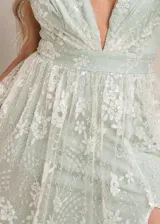 Vestido largo de fiesta con escote en V profundo, confeccionado en tul con bordados florales y detalles de glitter. Presenta una cintura marcada y falda con caída fluida.