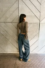 Chaqueta corta de tejido tipo encaje color verde oliva, con escote pico, manga larga acampanada y detalle de volantes en el borde del escote y los puños. Cierre frontal mediante lazadas.