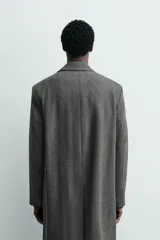Abrigo regular fit de color gris oscuro, confeccionado en tejido con mezcla de lana de origen italiano. Cuenta con cuello con solapas de muesca, manga larga, bolsillos de vivo en la cadera, bolsillo interior, abertura en el centro de la espalda y cierre frontal de botonadura.