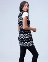 Chaleco largo tejido con cuello solapa, bolsillos delanteros, pasadores en la cintura y lazo para ajustar. Diseño con patrón de zigzag en blanco y negro.