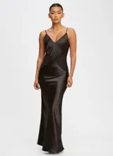 Vestido largo de satén negro con escote en V y tirantes finos. Presenta paneles laterales de malla que crean un diseño geométrico en la cintura y el torso, aportando un toque moderno y sofisticado a la silueta fluida.