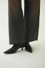 Pantalón de jean de corte amplio, color gris oscuro con efecto desgastado y manchas marrones. Tiro alto y largo hasta los tobillos.