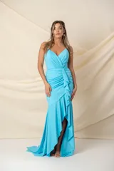 Vestido largo de fiesta color celeste, con breteles finos cruzados en la espalda, escote en V, drapeado en la parte superior, volados desde la cintura y abertura lateral.