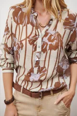 Camisa de manga larga con estampado floral en tonos marrones y negros, cuello mao y cierre frontal parcial con botones.