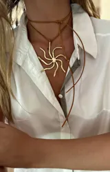 Collar con dije grande de bronce con forma de sol o estrella estilizada con ocho puntas onduladas. Se sostiene con un cordón de cuero sintético marrón que se ata al cuello.