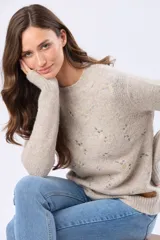 Buzo tejido de punto en color beige, con cuello redondo, mangas largas y delicados bordados multicolores en el frente.