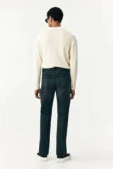 Jean de cinco bolsillos en denim de algodón rígido, color azul oscuro lavado. Modelo de cintura clásica con cierre de botón y corte relajado de cadera a bajo con pierna recta más amplia a partir del muslo.