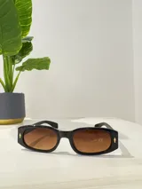 Lentes de sol rectangulares con montura de acetato negra y lentes marrones degradé.