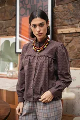 Camisa de broderie color chocolate, con cuello alto con volados, cierre frontal de botones y mangas largas con volumen.
