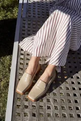 Mocasines de cuero vacuno con textura grabada color beige, diseño de punta cuadrada y taco bajo de madera.