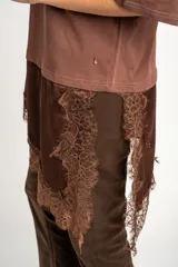 Remera oversize marrón con corte a la altura de la cadera, cuello redondo y mangas cortas holgadas. Incorpora un aplique inferior superpuesto de satén con detalles de encaje bordado en los bordes.
