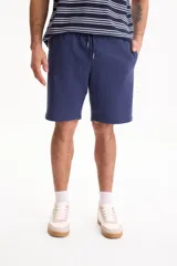 Bermuda deportiva sin friza color azul marino, con cintura elástica con cordón ajustable y bolsillos laterales.
