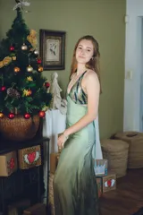 Vestido largo con estampado tie-dye en tonos violeta y fucsia, escote en V con detalles bordados dorados, cut-outs laterales bajo el busto y tirantes finos que se cruzan y atan en la espalda.