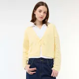 Chaqueta de punto con textura de croché en color amarillo pastel, con diseño de cuello en V, cierre frontal con lazada y terminaciones festoneadas en mangas y ruedo.