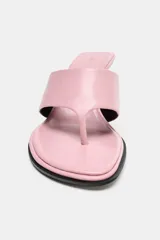 Sandalia tipo mule de piel color rosado, con diseño de tira ancha frontal y separación para el dedo. Cuenta con tacón fino de altura media en color negro y punta redonda.