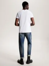 Remera blanca de algodón con corte slim, cuello redondo y mangas cortas con ribete rojo y azul. Logo de Tommy Hilfiger bordado en el pecho.
