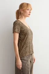 Remera de manga corta con escote en V, confeccionada en tela con estampado animal print en tonos tostados.