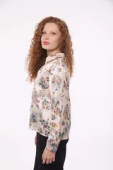 Camisa de manga larga con estampado de flores azules sobre fondo color crema, con cuello clásico y cierre frontal con botones.