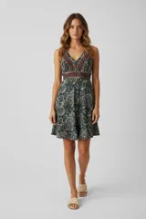 Vestido corto de corte holgado con escote en V, sin mangas y falda con vuelo. Presenta un diseño estampado con motivos geométricos y florales en tonos oscuros.