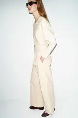 Pantalón de tiro alto con pinzas delanteras, bolsillos frontales y falsos bolsillos de vivo en la espalda. Presenta una pernera recta y cierre frontal con cremallera, botón interior y gancho.