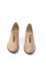 Zapatos de cuero color crema, con diseño cerrado tipo botineta de caña baja, puntera reforzada en charol y taco cuadrado de madera de 5 cm. Presenta un detalle de hebilla metálica dorada en el empeine.