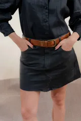 Minifalda negra de cuero con bolsillos delanteros y costuras decorativas en color ocre.