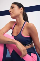 Top deportivo bicolor azul y rosa con breteles finos y banda elástica con logo de la marca.