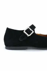 Zapato tipo Mary Jane de gamuza color negro, con punta redondeada y tira sobre el empeine con hebilla plateada.