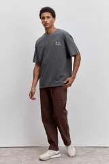 Pantalon de corte recto en color marron, confeccionado en tela resistente, con bolsillos laterales tipo parche y cierre frontal.