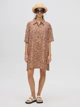 Camisa tipo vestido de corte oversize, confeccionada en viscosa con estampado abstracto en tonos marrones y rosados. Presenta cuello clásico, cierre frontal con botones y mangas cortas.