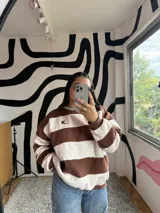 Buzo de corte holgado con diseño de rayas horizontales anchas en color chocolate y crudo. Presenta cuello redondo en color verde menta y puños elásticos.