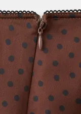 Minifalda marrón satinada con estampado de lunares negros y detalle de puntilla de encaje negro en el ruedo.