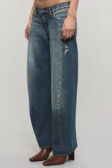 Jeans de tiro bajo confeccionados en denim 100% algodón, con diseño de pierna curva y sutiles desgastes en tono azul vintage.