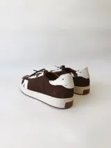 Zapatilla deportiva de cuero con estampado de vaca (pelo), color marrón y blanco. Suela blanca gruesa.