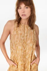 Vestido midi verde de lino italiano, con diseño sin mangas, cuello redondo y estampado de líneas onduladas punteadas. Cuenta con bolsillos laterales.