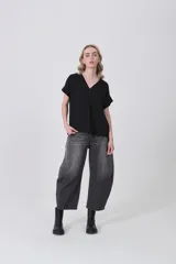 Blusa negra de poliéster con cuello en V, corte holgado y detalle de pinza central en el frente. Posee mangas cortas con dobladillo.