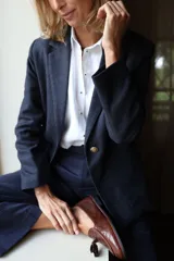 Blazer femenino forrado de corte tradicional, levemente entallado en la cintura, con mini hombreras. Presenta un botón metálico decorativo con escudo y costuras en tono contraste.