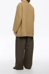 Chaquetón de corte recto confeccionado en mezcla de lana doble faz, con doble botonadura frontal, cuello con solapa, manga larga y bolsillos de tapeta.