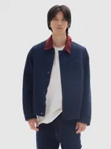 Campera de brim bull color azul marino con cuello de pana color bordó. Tiene bolsillos delanteros, cierre frontal metálico y forro interior de paño cuadrillé.