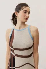 Vestido largo de punto con diseño geométrico y de ondas en color negro y crudo, sin mangas, con escote halter y detalle de flecos en el ruedo.
