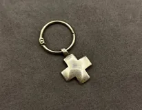 Set de tres llaveros de metal plateado con motivos religiosos, incluyendo un dije circular con la imagen del Sagrado Corazón de Jesús, un dije circular pequeño con una cruz y un dije con forma de cruz griega.