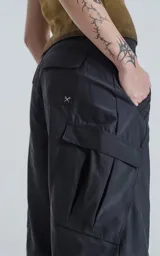 Pantalón cargo negro convertible, con cierre en la parte media de la pierna que permite transformarlo en un short ancho. Presenta bolsillos cargo a los lados y un corte holgado.