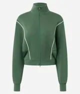 Campera deportiva de microfibra color verde oscuro, con cuello alto, manga larga y cierre frontal. Presenta recortes estructurados con vivos contrastantes claros, barra ajustada y puños alargados.
