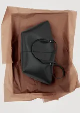 Bolso shopper negro con efecto piel, dos asas de hombro y cierre de botón magnético.