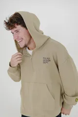 Canguro beige con capucha, cierre frontal parcial y bolsillo tipo canguro. Presenta estampado con texto en el pecho y detalle de etiqueta en la manga.