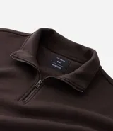 Buzo de corte holgado tipo ballon, color marrón oscuro, con cuello alto y cierre frontal parcial. Presenta mangas largas con puños elásticos y cordón ajustable en el ruedo.