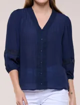 Blusa blanca de bambula con escote en V, pechera de encaje y mangas 3/4 abullonadas con detalles de puntilla.