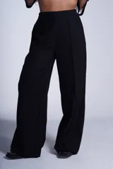 Pantalón de corte amplio y tiro alto, color beige, con elástico en la cintura trasera, pinzas frontales marcadas y bolsillos laterales.