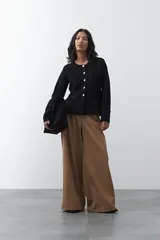Cardigan negro de tejido de punto con cuello redondo y cierre frontal con botones a contraste. Presenta un corte entallado en la cintura con una silueta levemente evasé y mangas largas.
